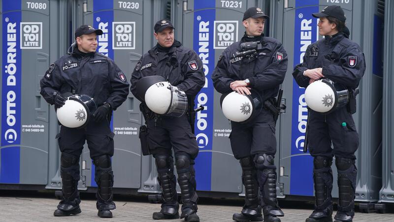 Polizeibeamte stehen vor mobilen Toilettenhäuschen neben dem Gästeblock.