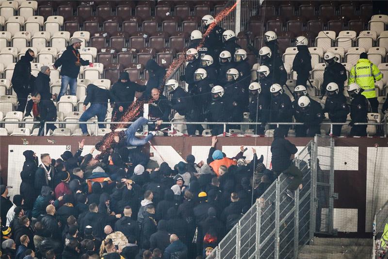 Polizeikräfte drängen randalierende Fans von Dynamo Dresden zurück in den Gästeblock. Foto: Christian Charisius/dpa