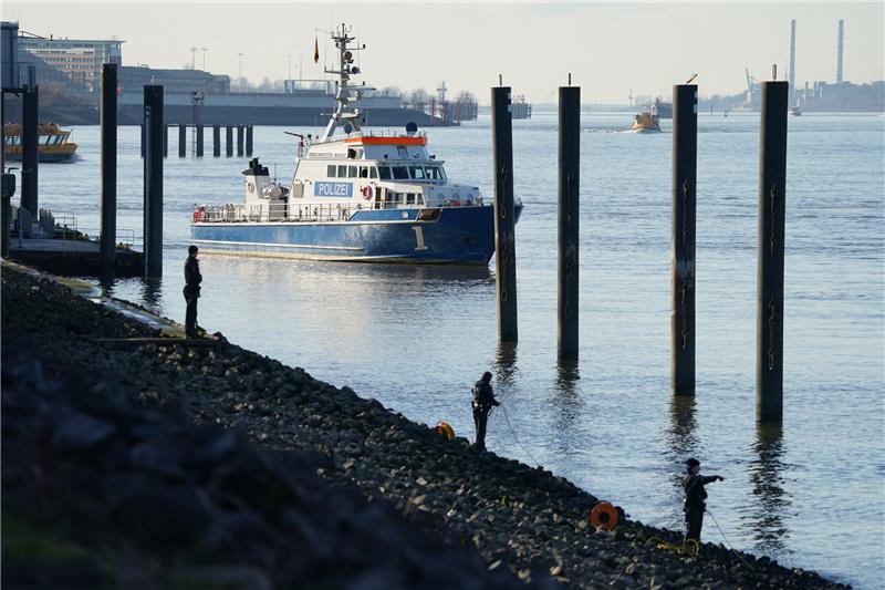 Junge versinkt nahe Finkenwerder in Elbe – Suche abgebrochen Polizeitaucher und Polizeibeamte suchen in der Elbe nach einem vermissten Jungen. Foto: dpa-Bildfunk