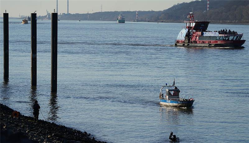 Polizeitaucher und Polizeibeamte suchen in der Elbe nach einem vermissten Jungen. Am Hamburger Fähranleger Bubendey-Ufer wird seit Dienstagvormittag in einem Großeinsatz der Polizei nach einem Jungen gesucht, der dort in die Elbe gefallen sein soll. Augenzeugen hatten versucht, das augenscheinlich zehn bis zwölf Jahre alte Kind aus dem Wasser zu holen, jedoch ohne Erfolg. Daraufhin ging der Junge nach Berichten der Helfer unter und tauchte nicht wieder auf. Die Polizei sucht nun mit Tauchern, Beamten an Land und Hubschraubern nach dem Jungen. Foto: Marcus Brandt/dpa