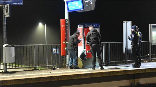 Polizisten begutachten das Ausmaß der Sprengung, der DB-Fahrkartenautomat am Bahnhof Agathenburg ist stark beschädigt.