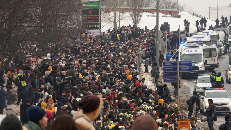 Polizisten beobachten, wie Menschen zur Beerdigungszeremonie des russischen Oppositionellen Nawalny gehen.