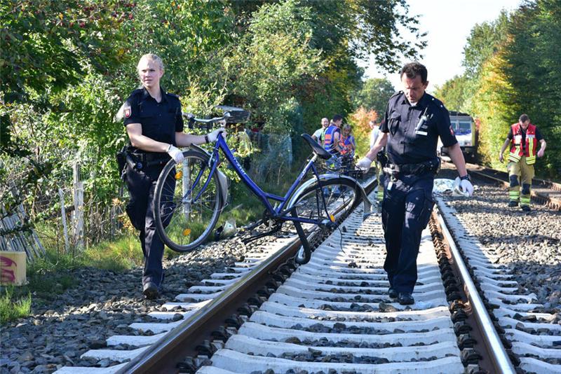 Polizisten bergen das Fahrrad der Schülerin, es hatte sich nach dem Unfall in einem Zaun am Rand der Bahnstrecke verfangen. Foto: Beneke