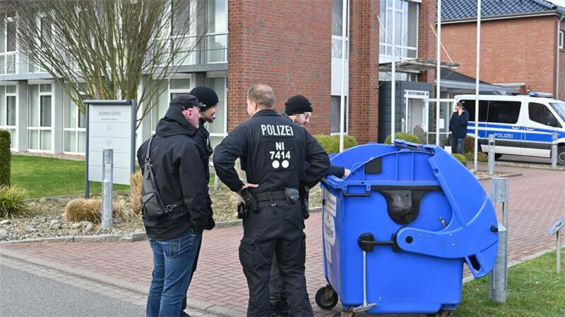 Polizisten durchsuchen vor der Co.Net-Zentrale in Drochtersen einen Altpapiercontainer.