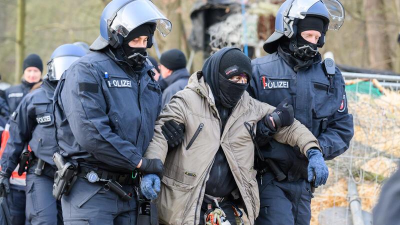 Polizisten führen einen entkräfteten Aktivisten aus dem Protestcamp ab.