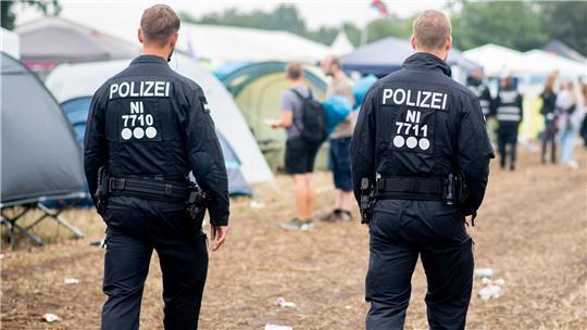 Polizisten gehen über den Zeltplatz des Deichbrand Festivals.