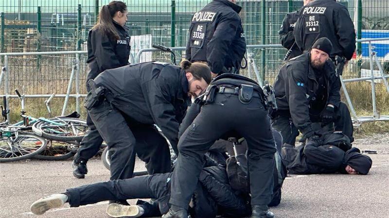 Musk live bei AfD-Wahlkampfshow zugeschaltet Polizisten halten Demonstranten am Boden fest. Sie hatten zuvor versucht mit Fahrrädern Richtung Veranstaltungshalle vorzudringen.