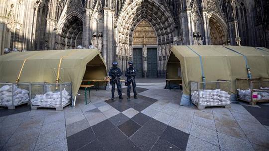 Polizisten mit Maschinenpistolen stehen vor dem Kölner Dom. Nach dem Terroralarm für das Gotteshaus sind drei weitere Verdächtige festgesetzt worden.