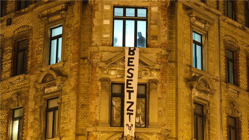 Polizisten sind in einem leerstehenden Haus im Leipziger Osten, an dessen Fassade ein Transparent mit der Aufschrift „Besetzt“ häng