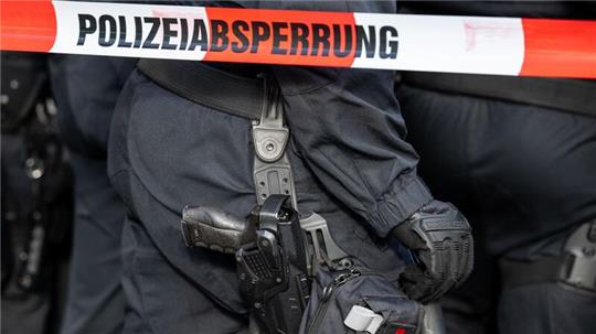 Polizisten stehen hinter einem Polizei-Flatterband.