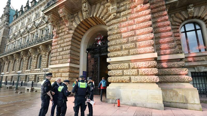 Polizisten stehen vor dem Rathauseingang, der mit Farbe beschmiert ist.