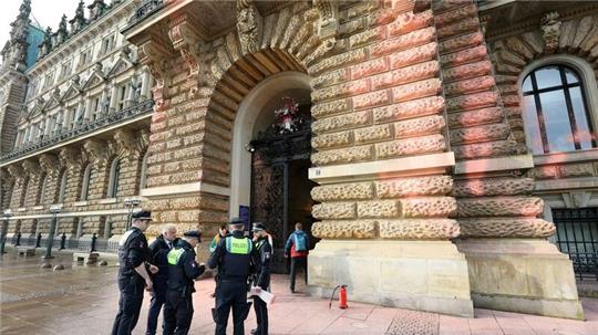 Polizisten stehen vor dem Rathauseingang, der mit Farbe beschmiert ist.