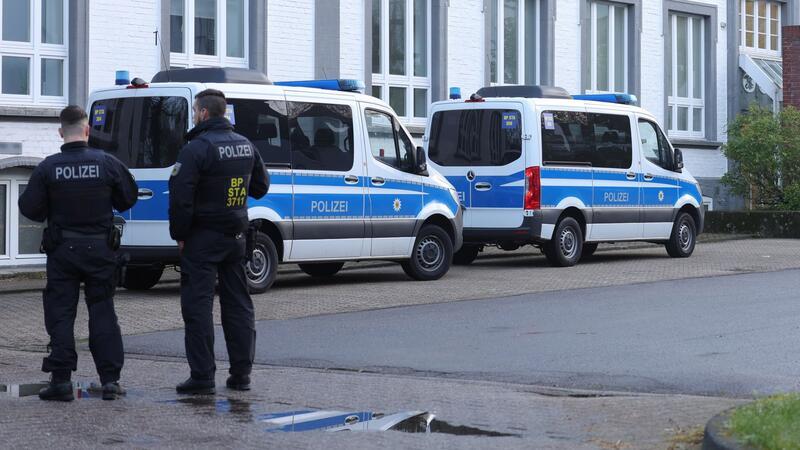 Großrazzia gegen Schleuser: Ausländerämter bestochen? Polizisten stehen vor einem Gebäude, das durchsucht wird.