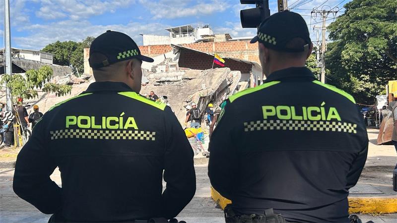 Polizisten stehen vor einem abgestürzten Gebäude.