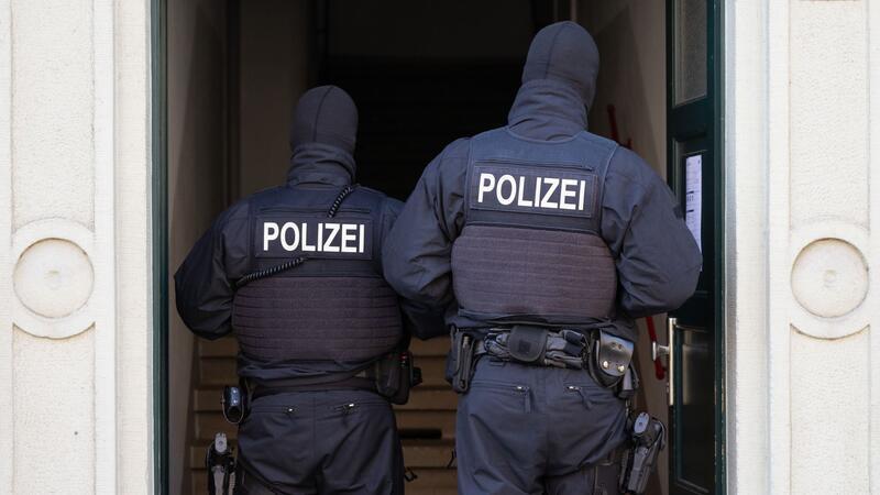 Polizisten stehen während einer Razzia in einem Hauseingang (Symbolbild).