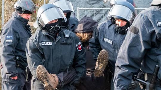 Polizisten tragen einen Demonstranten weg bei der Räumung des Protestcamps „Tümpeltown“.