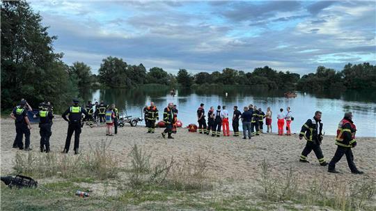 Polizisten und Feuerwehrleute stehen am See Hinterm Horn in Hamburg. (Archivbild)