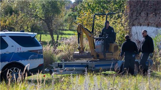 Polizisten untersuchen mit einem Bagger ein Grundstück in Herzberg (Landkreis Oder-Spree).
