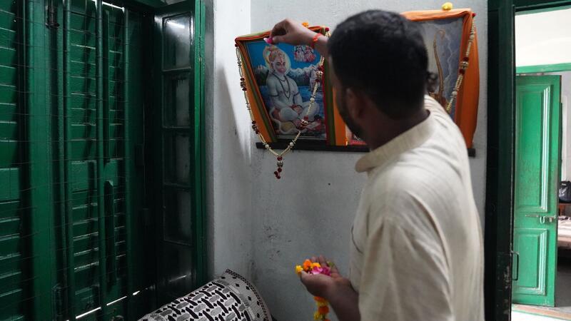 Priester Kalikant Dubey schmückt ein Bild von Gott Hanuman in seinem Büro.