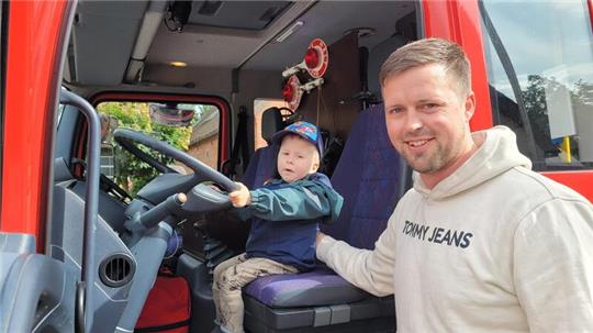 Während sich Papa Marcel Bursky über eine großzügige Spende freut, blüht Söhnchen Theo auf dem Fahrersitz des Feuerwehreinsatzwagens auf.