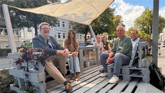 Prof. Dr. Karsten Ley (links), Architekturstudentin Nina Garbers (Zweite von links) sowie Mitglieder des Vereins Buxtehude im Wandel nehmen zur Einweihung Platz.