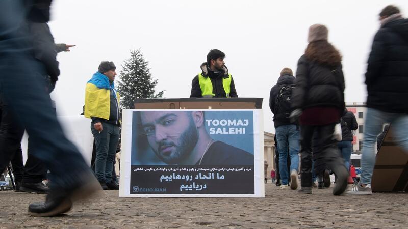 Zeitung: Iranischer Rapper Salehi zum Tode verurteilt Protestaktion gegen Irans Staatsführung auf dem Pariser Platz in Berlin. Auf dem Plakat ist der Rapper Salehi zu sehen.