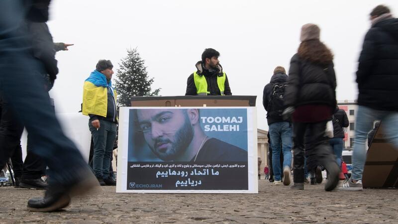 Protestaktion gegen Irans Staatsführung auf dem Pariser Platz in Berlin. Auf dem Plakat ist der Rapper Salehi zu sehen.