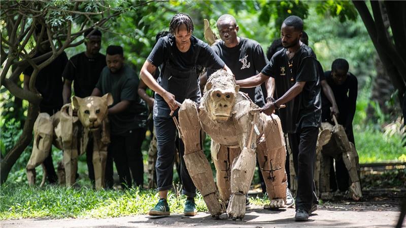 Puppenspieler bewegen Papptiere durch die botanischen Gärten von Kinshasa. Dies sind die ersten Schritte von „The Herds“, einer bewegenden Theateraufführung, die von der Demokratischen Republik Kongo bis zum Polarkreis reisen wird, um auf die Klimakrise aufmerksam zu machen.