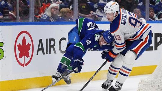 Quinn Hughes von den Vancouver Canucks wird von Ryan Nugent-Hopkins von den Edmonton Oilers zu Fall gebracht.