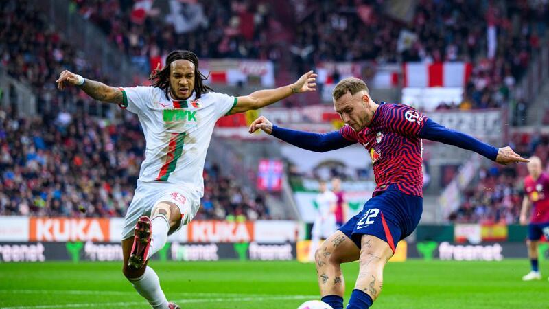 Fan-Proteste in der Bundesliga - Union-Partie vor Abbruch RB-Profi David Raum (r) flankt gegen den Augsburger Kevin Mbabu.