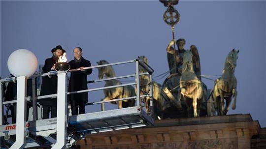 Rabbiner Yehuda Teichtal (l.) und Bundeskanzler Olaf Scholz zünden beim traditionellen zentralen Chanukka-Lichterzünden am Brandenburger Tor in Berlin ein Licht an.