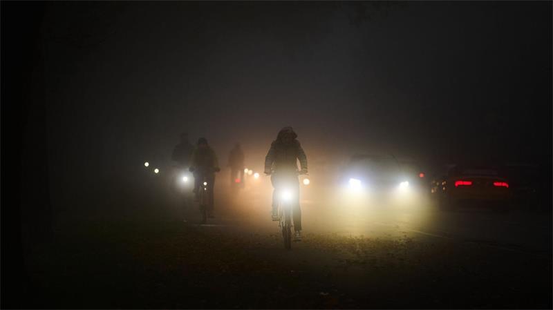 Rad- und Autofahrer fahren am frühen Morgen im Nebel über den Osterdeich.