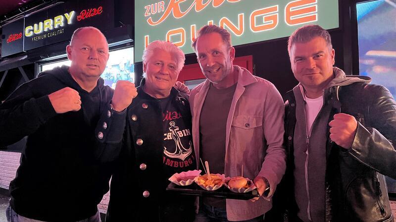 Ralf Kimmel (links) und André Gretesch (rechts) nehmen den Wirt der Reeperbahn-Kultkneipe Ritze, Carsten Marek, und dessen Anwalt Dr. Alexander Schneehain (mit einer Portion Curry-Wurst und Pommes) vor dem Imbiss in die Mitte.