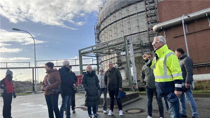 Ralf Thalinger (gelbe Jacke) führt die Besuchergruppe über das Kraftwerksgelände an der Elbe.