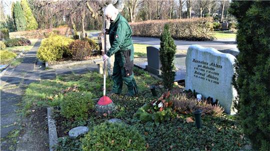 Regelmäßige Pflege muss sein, auch im Winter: Friedhofsgärtner Joachim Scharnberg recht das Laub von einem Grab auf dem Langener Friedhof. Foto: Schoener