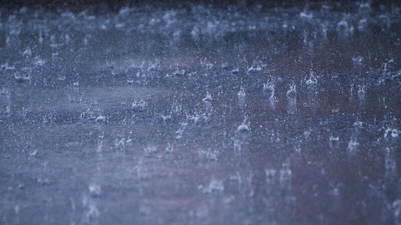 Regen prasselt auf die Straße.
