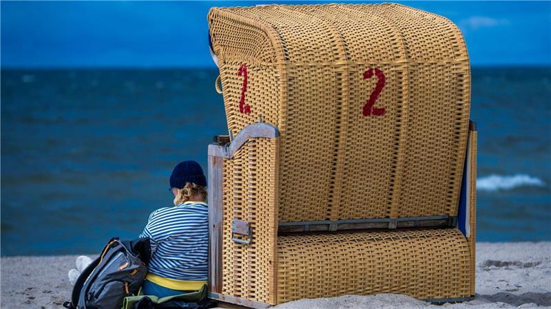 Bilder des Tages Regenschauer und kräftiger Wind an der Ostseeküste: Eine Frau sitzt mit Mütze bei wechselhaftem Wetter neben einem Strandkorb auf der Insel Poel.