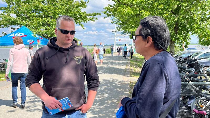 Omas gegen Rechts protestieren gegen AfD-Stand am Lühe-Anleger Reiner Sprenger als Blockomat - Protest-Idee: AfDler im Gespräch binden - redet mit AfD-Vize Sebastian Sieg.