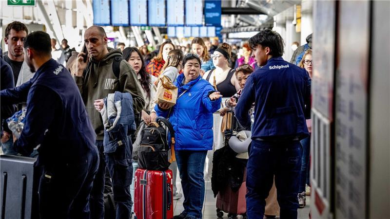 Reisende stehen Schlange am Serviceschalter der Fluggesellschaft KLM am Flughafen Schiphol. 