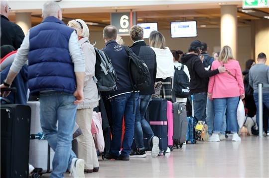 Reisende stehen im Terminal 1 im Flughafen Hamburg an einem Check-In-Schalter an. Foto: Bodo Marks/dpa