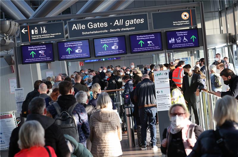 Reisende stehen in einer langen Schlange vor der Sicherheitskontrolle im Flughafen Hamburg. Foto: Christian Charisius/dpa
