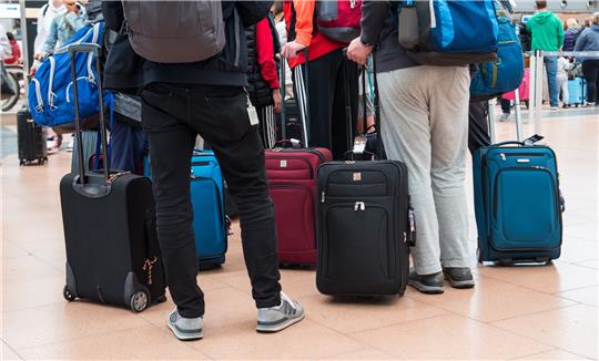 Reisende stehen mit ihrem Gepäck am Flughafen. Foto: Daniel Bockwoldt/dpa