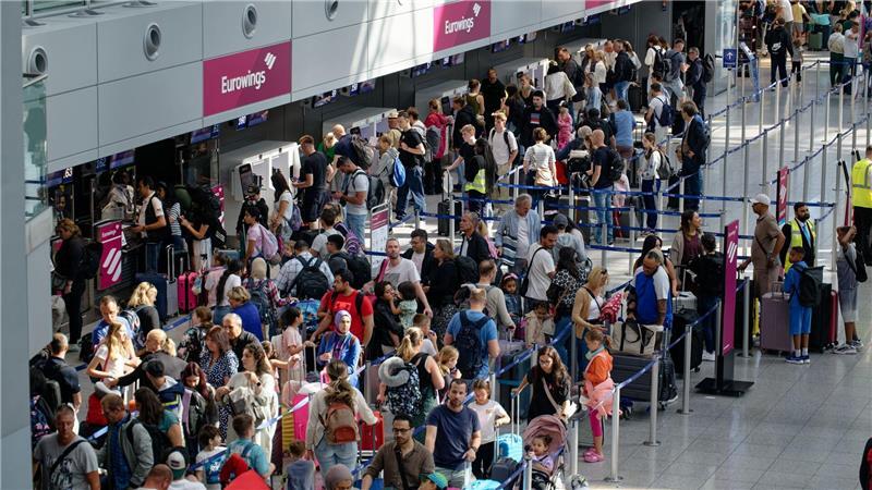 Bilder des Tages Reisende warten an Schaltern im Flughafen Düsseldorf auf die Abfertigung.