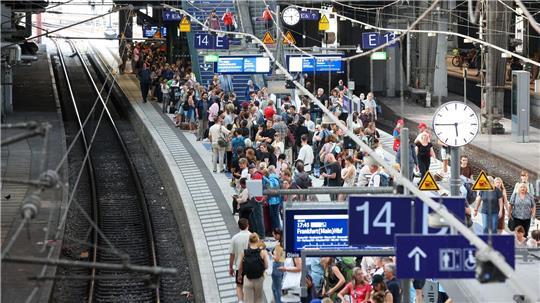 Reisende warten im Hauptbahnhof Hamburg auf einem Zug.