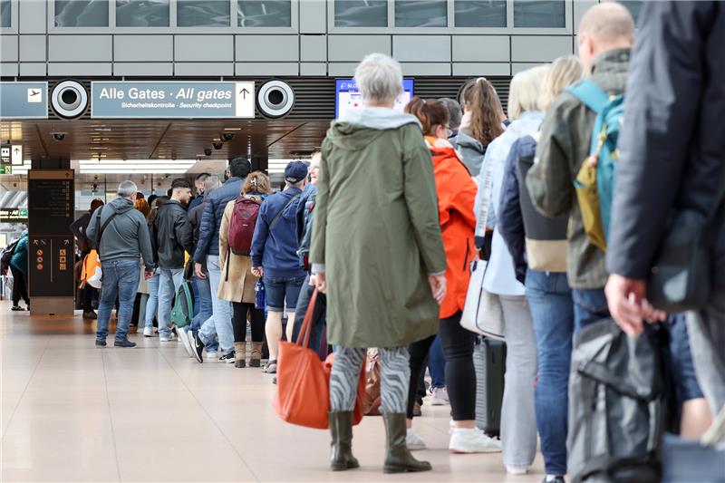 Reisende warten in langen Schlangen vor der Sicherheitskontrolle am Flughafen Hamburg auf die Abfertigung. Foto: Marks/dpa