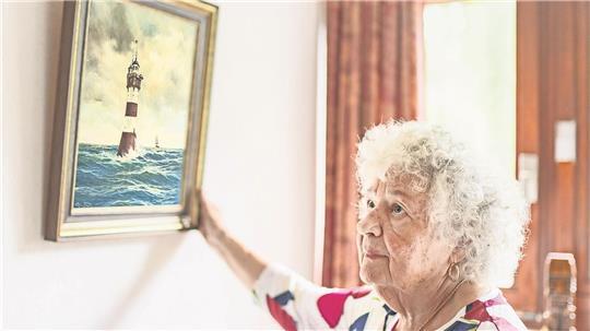 Renate Beese und das Bild vom Leuchtturm „Roter Sand“, das sie hat malen lassen.