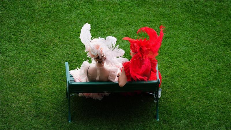 Rennbesucherinnen sitzen auf einer Bank am ersten Tag des Royal Ascot auf der Pferderennbahn von Ascot.
