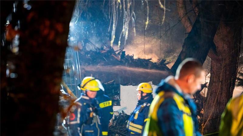 Reste des abgebrannten Hauses qualmen während den Nachlöscharbeiten hinter Einsatzkräften des THW.