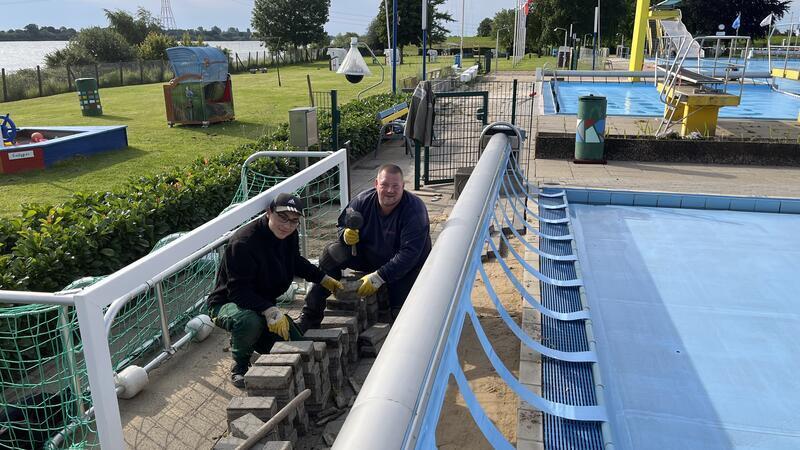 Retter nach dem Rohrbruch: Die Winckler-Mitarbeiter Reiner Pape und Lucas Gräschke bei den letzten Pflasterarbeiten im Freibad in Hollern-Twielenfleth (von rechts).