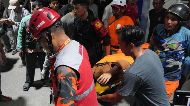Zahl der Toten bei Zugunglück in Indonesien steigt Retter tragen eine Frau auf einer Trage.